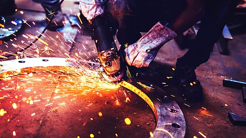 Worker grinding a casting with sparks flying during fettling and rework