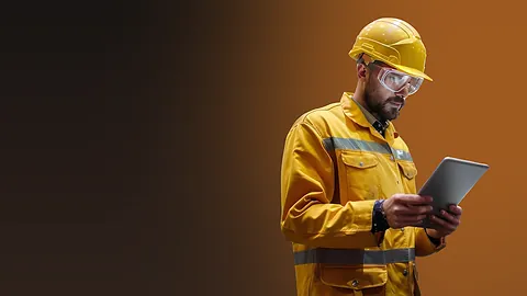 Quality inspector in a hard hat checking test results on a tablet